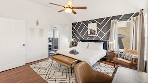 A modern hotel room with a bed, a bench, a chair, and a ceiling fan. - 5-BD Getaway w/ Pool, Patio, Firepit | Mins to DT (Dallas)