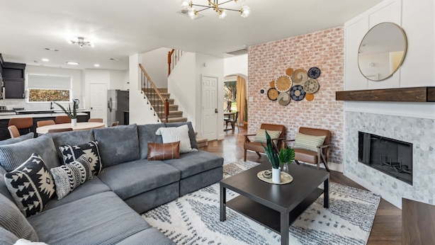 A modern living room with a gray sectional sofa, a coffee table, and a fireplace. - 5-BD Getaway w/ Pool, Patio, Firepit | Mins to DT (Dallas)