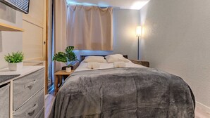 A bedroom with a bed, bedside tables, a potted plant, and a nightstand. - Alpine Ski-In/Out w/MountainView (Val Thorens)