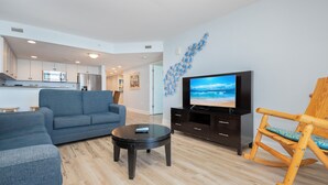 Una sala de estar moderna con sofá, una mesa de centro, televisor y una mecedora de madera.