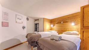 A cozy bedroom with two beds, wooden headboard, and a small window. - Mountain Hideaway near the Slope (Val Thorens)