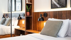 A modern hotel room with a large bed, a wooden headboard, a built-in shelf with a plant, and a large mirror. - Pivô Vila Nova by Viva - Conforto e Localização Privilegiada (São Paulo)