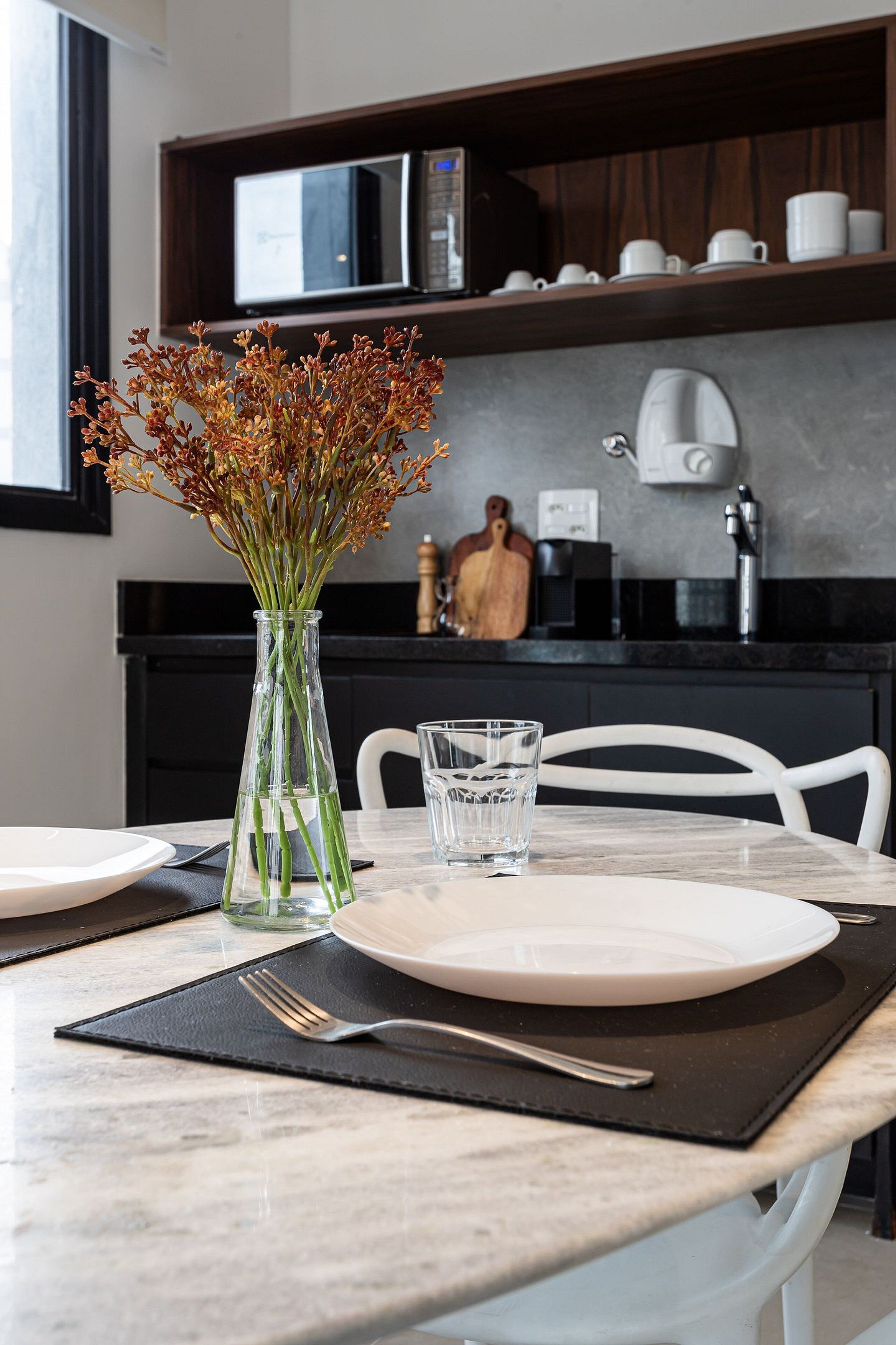 Ein Esstisch mit einer Blumenvase, Tellern, Besteck und einem Glas Wasser.
