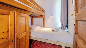 A single bed with a wooden headboard, a white mattress, and a small bedside table with a lamp. - Mountain-View with Ski-In ski Out Stay (Val Thorens)