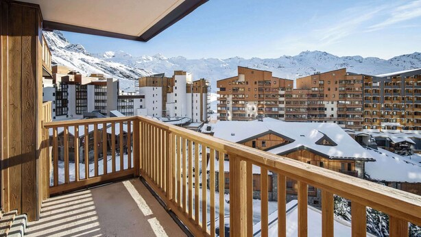 Ein Balkon mit Blick auf schneebedeckte Berge und moderne Gebäude.