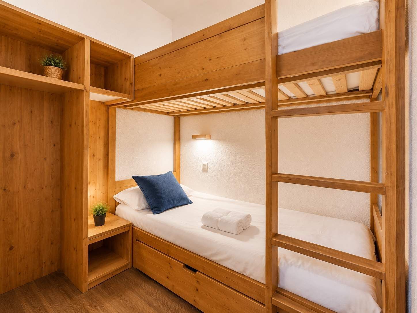 A bunk bed room with wooden walls and a small shelf with a plant.