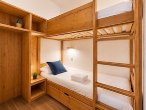 A bunk bed room with wooden walls and a small shelf with a plant.
