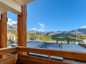 Ein Holzbalkon mit Blick auf eine gebirgige Landschaft und einen klaren, blauen Himmel.