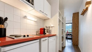 A modern kitchen with white cabinets, a red countertop, and a dishwasher. - Ski Side Nook in Town Center View (Val Thorens)