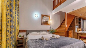 Ein Schlafzimmer mit einem Bett, einem Nachttisch, einem Spiegel, einer Lampe und einer Treppe.