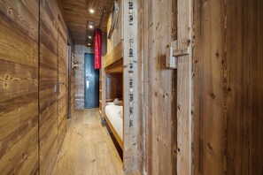 A narrow hallway with wooden walls and a bunk bed in the distance. - Mountain View Ski In Out Apartment (Val Thorens)