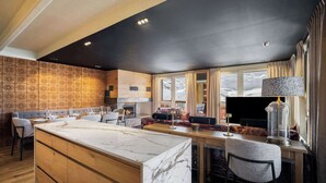 A modern kitchen with a marble island, wooden cabinetry, and a large window with a view of mountains. - Luxurious Apartment with Ski-In and Out Access in Centre (Val Thorens)