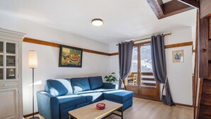 Ett vardagsrum med en blå soffa, ett soffbord i trä och en golvlampa.