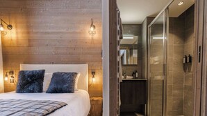 Ein Schlafzimmer mit einer Holzwand, einem Bett mit kariogeflochtenem Überwurf und zwei Kissen.