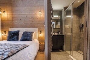 A bedroom with a wooden wall, a bed with a plaid blanket, and two pillows. - Megeve Luxury Spa Escape with views and parking (Megève)