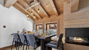 Ein Essbereich mit Holzbalkendecke, Kamin und Tisch für vier Personen.