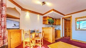 A cozy kitchen with wooden cabinets and a dining area with a table and chairs. - Alpine Stay w/ Private Ski Views (Val Thorens)