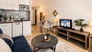 Un espacio habitable compacto con cocina, comedor y zona de estar con televisor.
