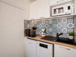 Eine kompakte Küche mit Mikrowelle, Kaffeemaschine und Geschirrspüler.