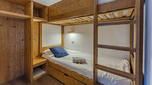 Quarto com beliche, paredes de madeira e uma estante.