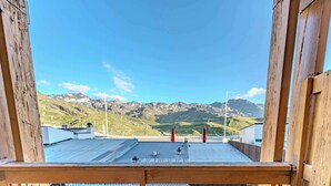 Varanda de madeira com cobertura metálica, vista para uma paisagem montanhosa.
