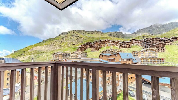 A mountain resort with wooden chalets and modern buildings, featuring a view of the surrounding hills and a clear sky. - Resort Access Flat (Val Thorens)