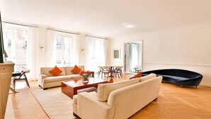 A spacious living room with a sofa, coffee table, and a dark accent chair. - EXCEPTIONAL SETTING ON RUE BUCI TO EXPERIENCE PARIS AT FINEST, SAINT-GERMAIN (Paris)