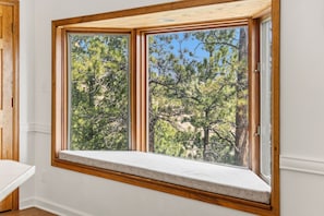 Ein Zimmer mit einem großen Fenster mit Blick auf einen Wald.