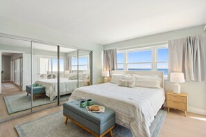 Ein Schlafzimmer mit einem großen Bett, einem Spiegel, einem Nachttisch und Meerblick.