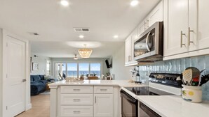 Una cocina moderna con armarios blancos, una isla central y vistas al exterior.