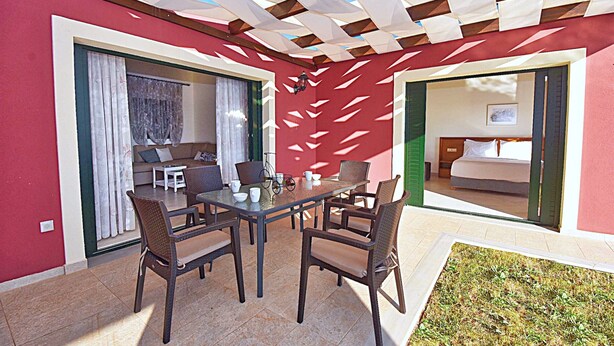 A dining area with a table and chairs, a sofa, and a bicycle. - Villa Triton (Corfu)