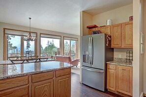 Eine moderne Küche mit Holzschränken, einem Edelstahlkühlschrank und einer großen Kochinsel mit Granitarbeitsplatte.