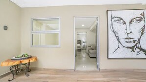 Un passadís amb una banca de fusta, un gran finestral i una porta que dona a una altra habitació.