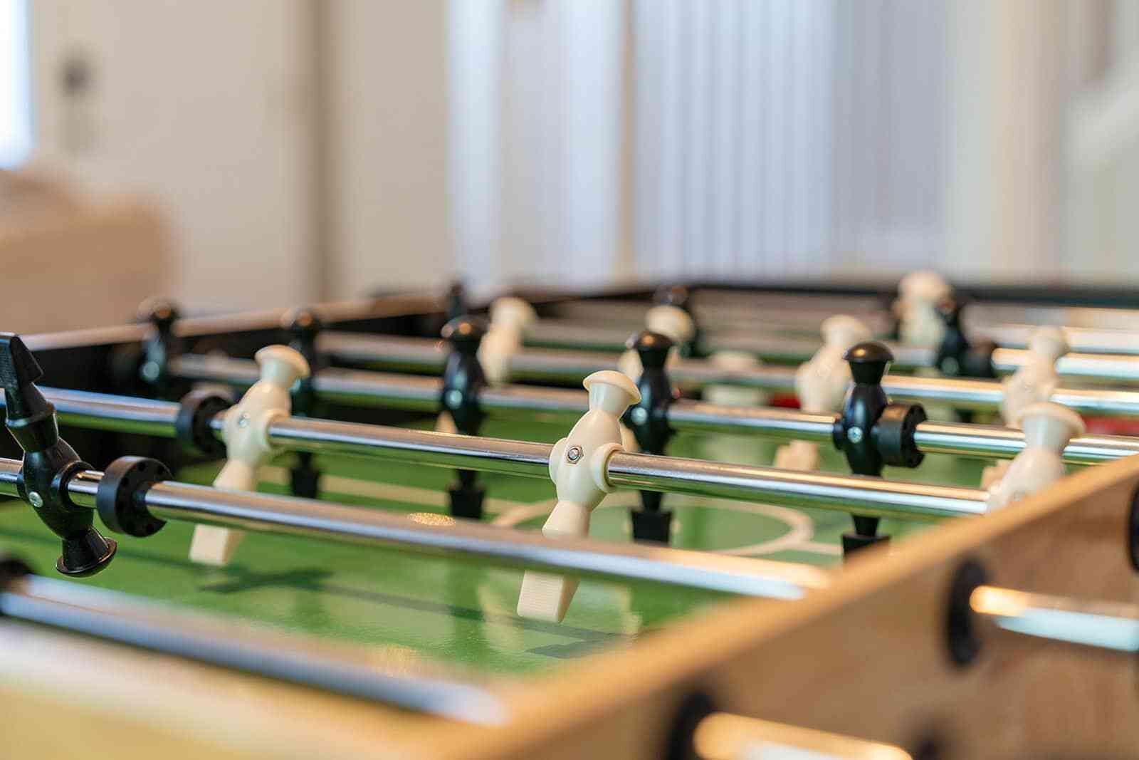 Une vue rapprochée d’un baby-foot, avec ses tiges métalliques et ses figurines en plastique.