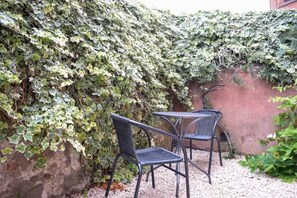 A patio with two metal chairs and a table, surrounded by a dense ivy-covered wall. - Cozy Edinburgh Flat - 2 Double bedrooms (Edinburgh)