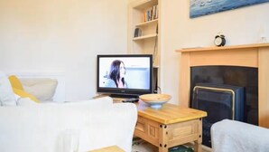 Ein gemütliches Wohnzimmer mit Fernseher, Kamin, Bücherregal und einem Gemälde an der Wand.
