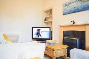 A cozy living room with a television, a fireplace, a bookshelf, and a painting on the wall. - Cozy Edinburgh Flat - 2 Double bedrooms (Edinburgh)