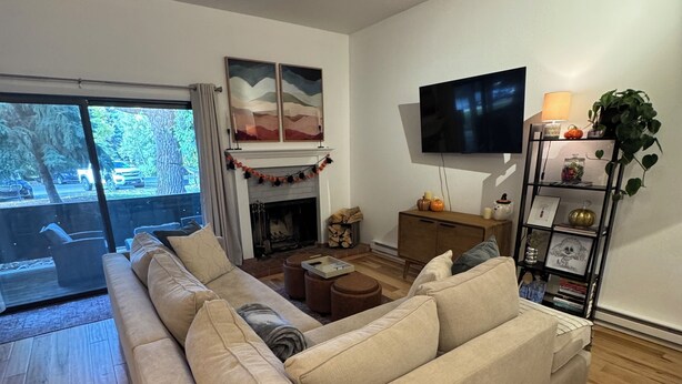 A living room with a beige sofa, a fireplace, a TV, and a bookshelf. - Serene 2-bedroom condo in Eagle-Vail, perfect for a fun getaway (Avon)
