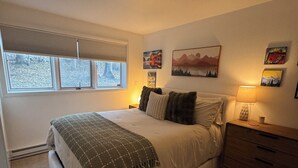 A bedroom with a bed, a nightstand, a dresser, and a window with blinds. - Serene 2-bedroom condo in Eagle-Vail, perfect for a fun getaway (Avon)