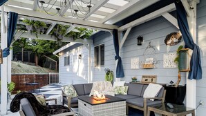 A covered outdoor seating area with a fire pit, cushioned seating, and a decorative rug. - The Napa Sanctuary • Vineyard Views • Hot Tub (Napa)
