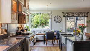 A modern kitchen with a central island, wooden cabinets, and a large window providing a view of the outdoors. - The Napa Sanctuary • Vineyard Views • Hot Tub (Napa)