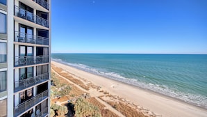 Un edificio alto con balcones que dan a la playa.