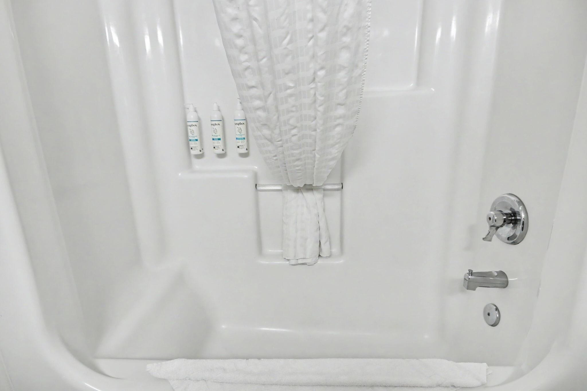 A bathtub with a shower curtain, a towel, and toiletries.