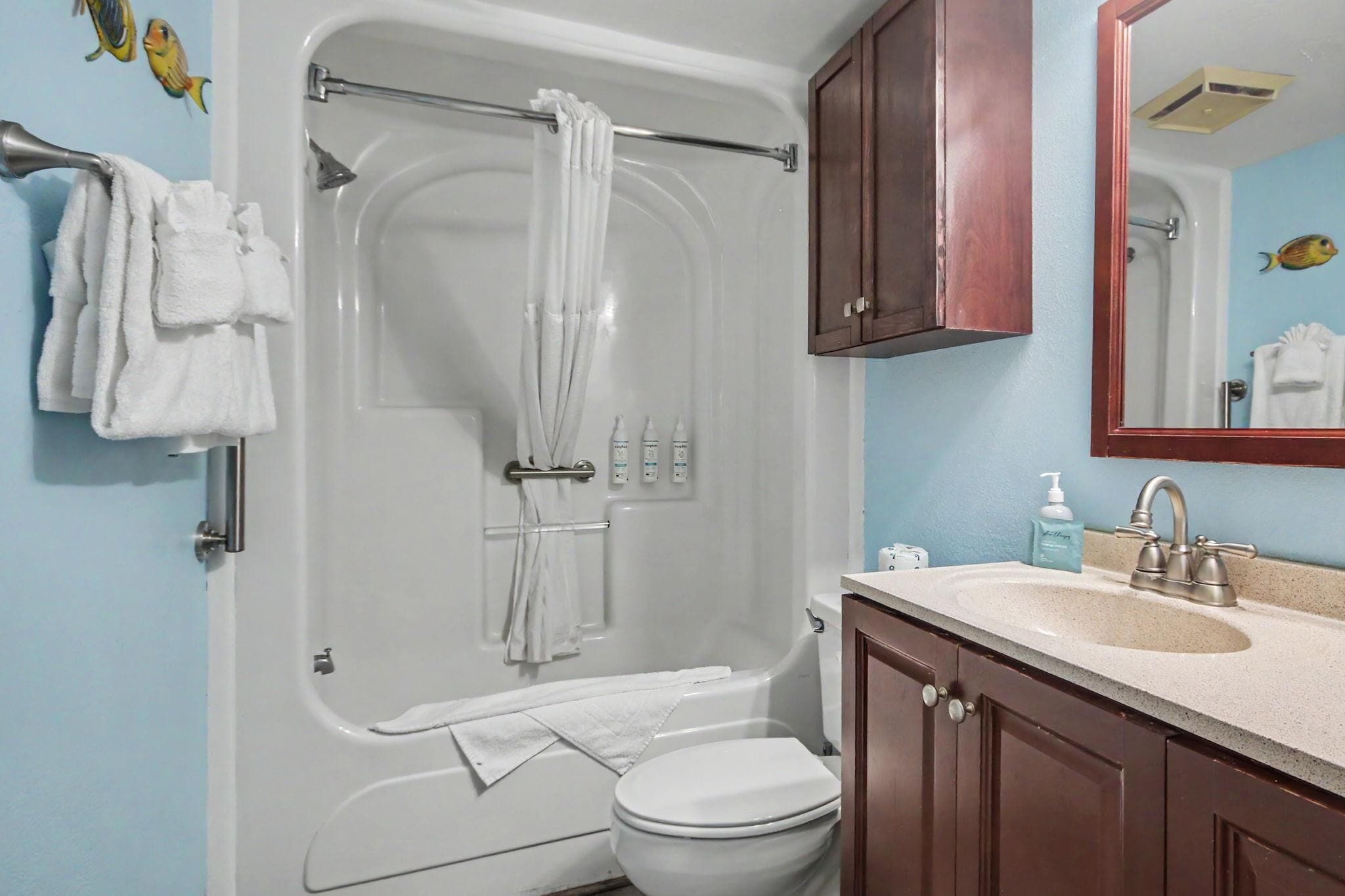 A bathroom with a bathtub, toilet, sink, and mirror.