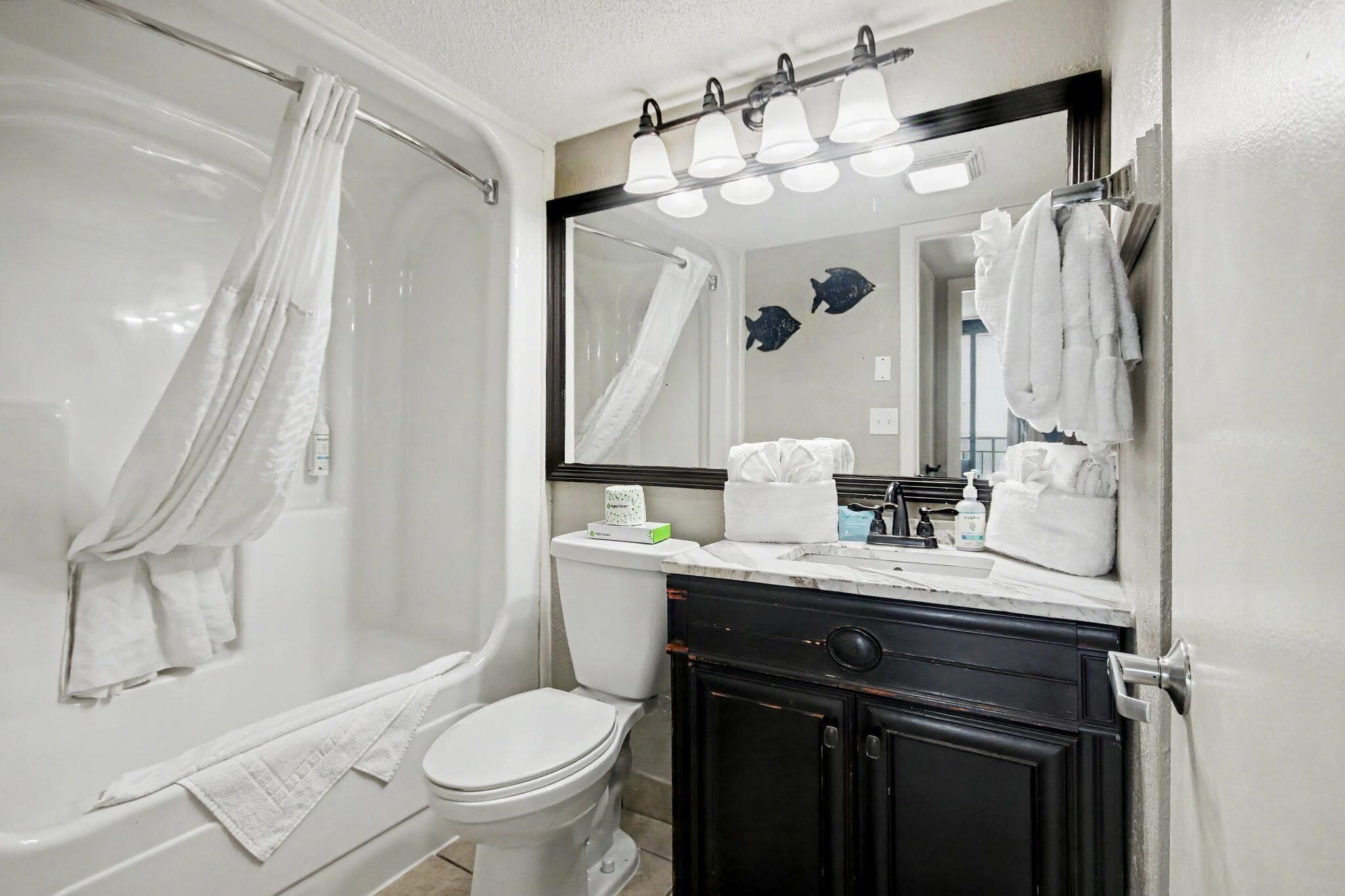 A bathroom with a bathtub, toilet, vanity with a mirror, and towels.