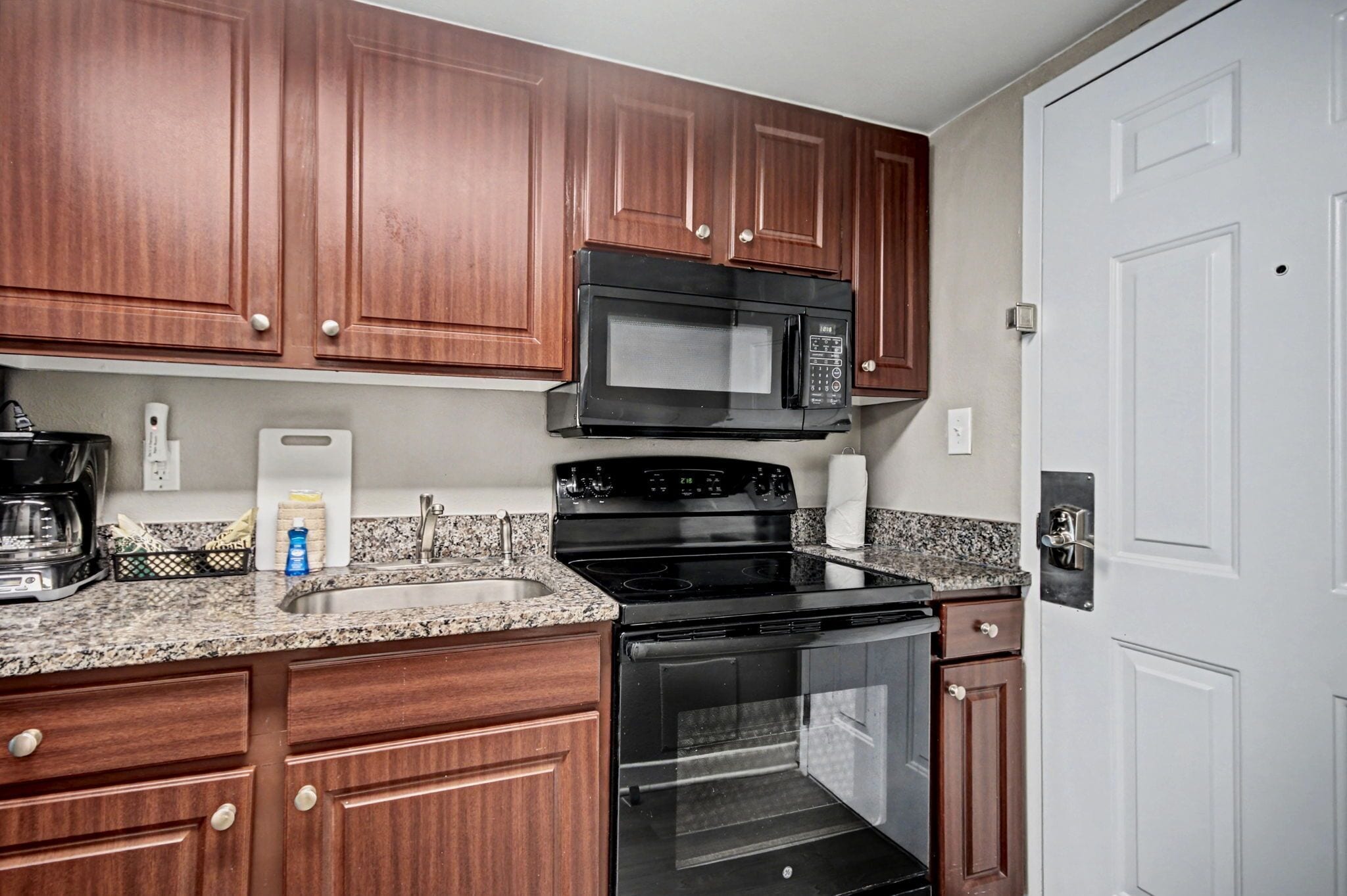 A kitchen with wooden cabinets, a black microwave, a stove, and a built-in oven.
