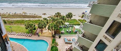 A hotel with a pool, beach view, and outdoor lounge area.