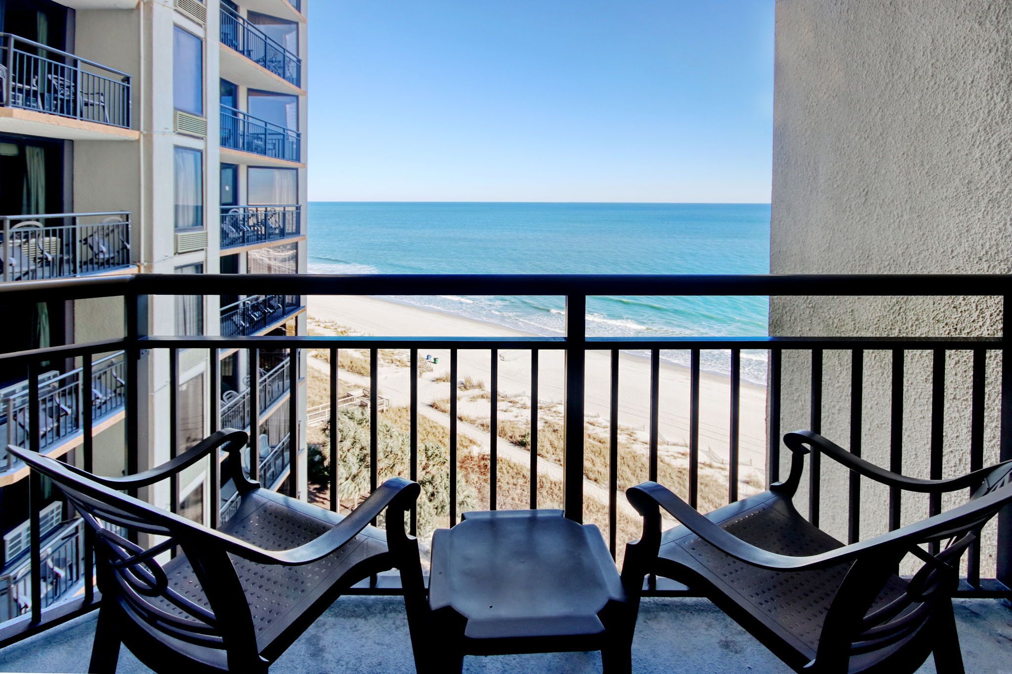 Een balkon met twee stoelen en uitzicht op het strand.