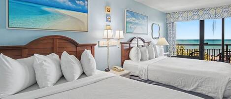 A hotel room with two beds, a view of the beach, a balcony, and a painting of a beach scene.