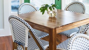 A dining area with a wooden table and wicker chairs, a green door, and a view of the outdoors.
